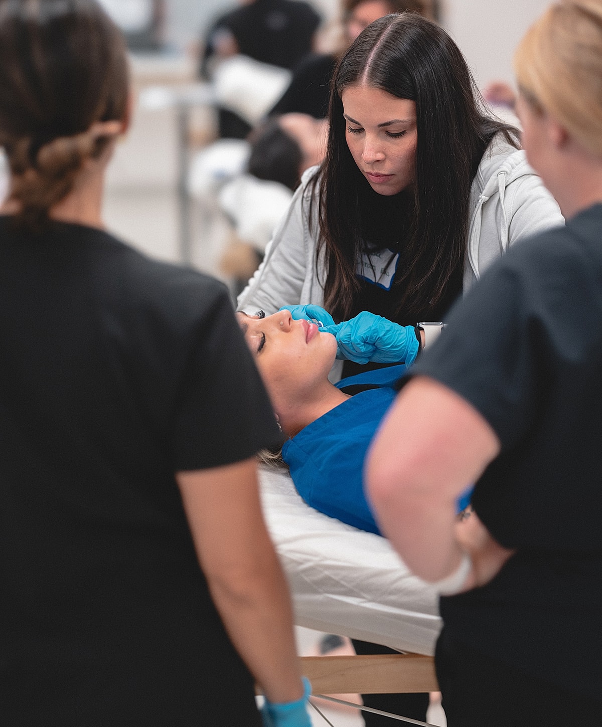 Facial treatment session with two professionals assisting.