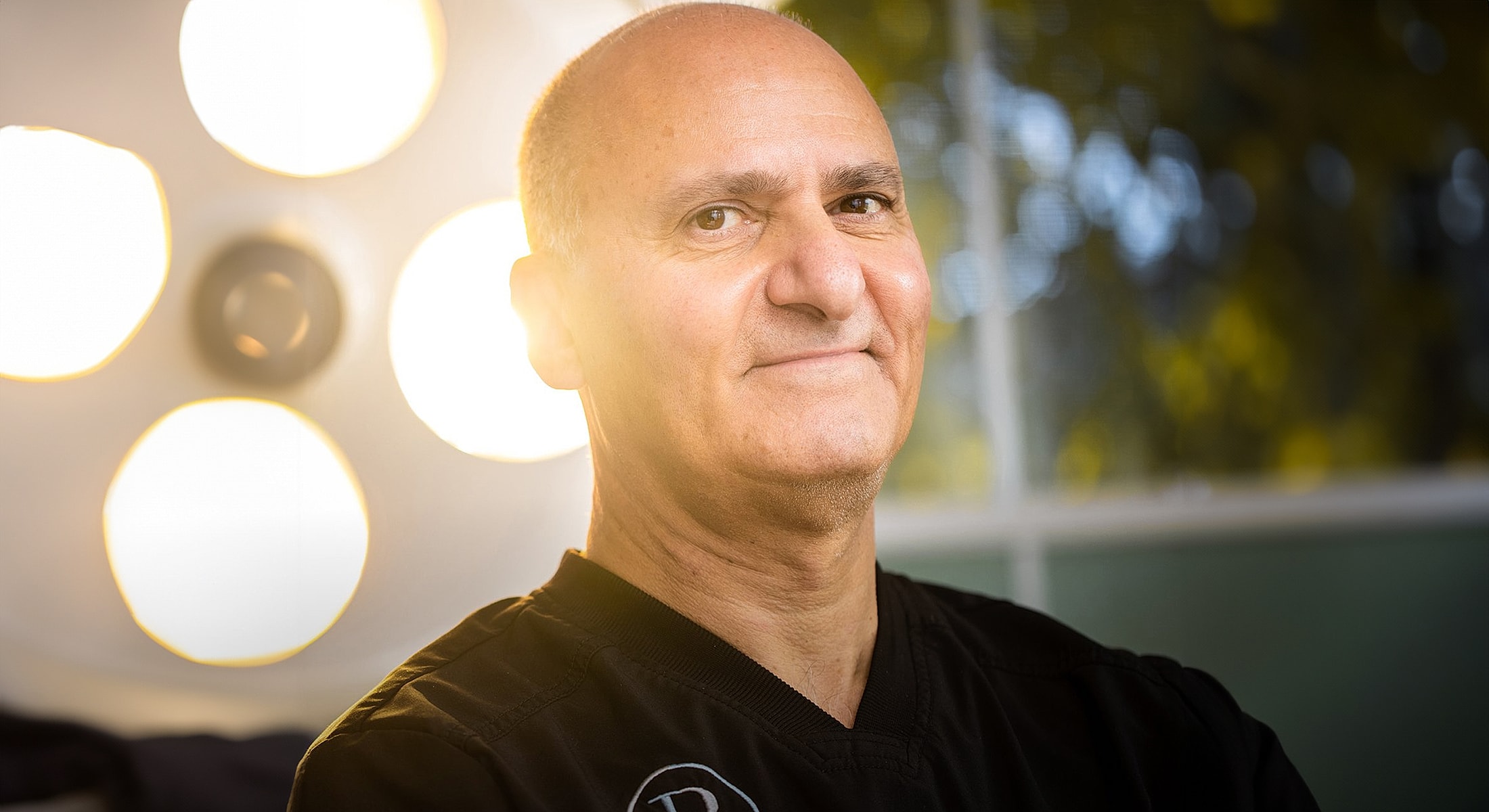 Man in medical attire smiling confidently.